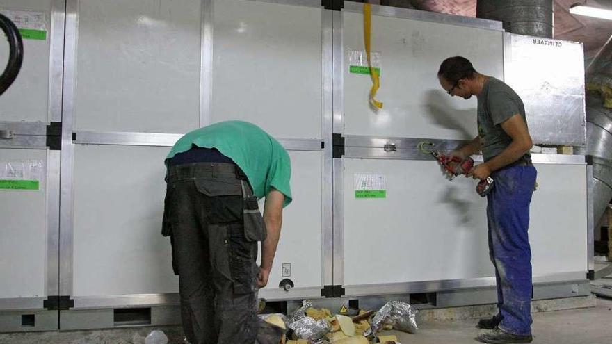 Operarios, ayer, trabajando en la instalación de las bombas de calor y de la climatizadora. // Bernabé