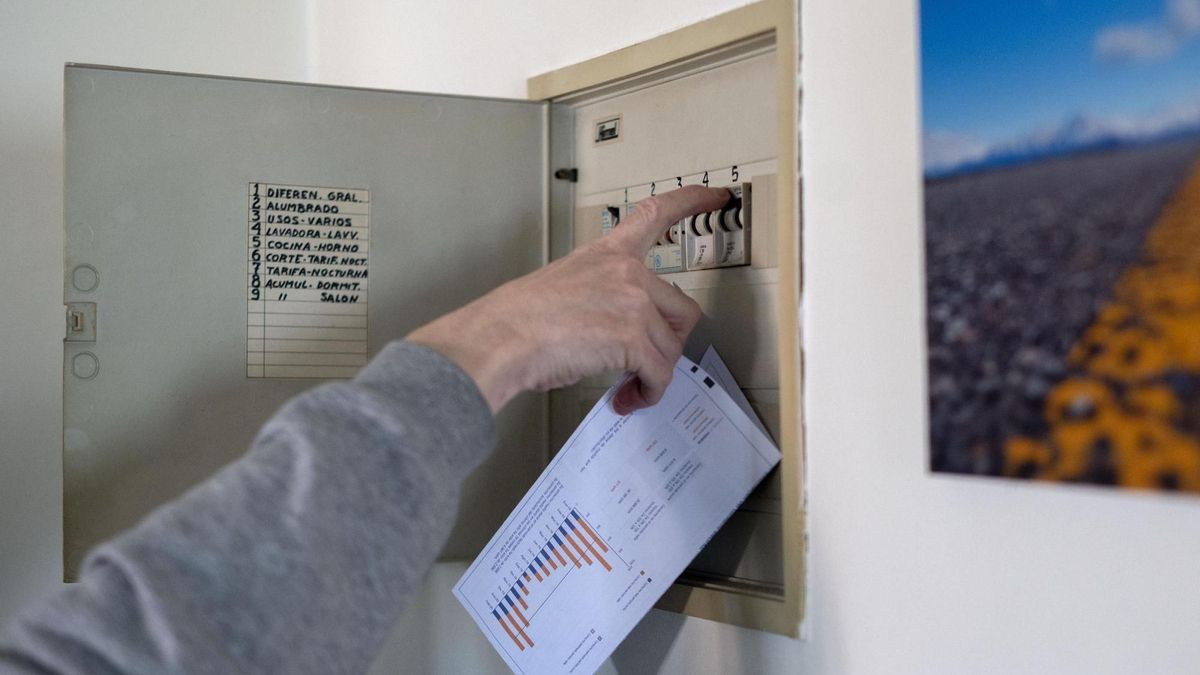 Un hombre sube los plomos de la luz con una factura de luz en la mano, en Madrid, (España).