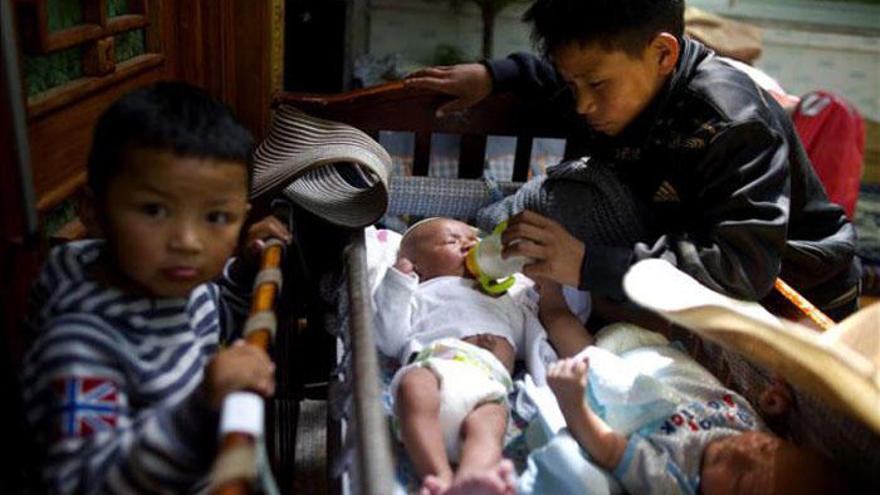 Un niño da alimento a un bebé en un orfanato chino.