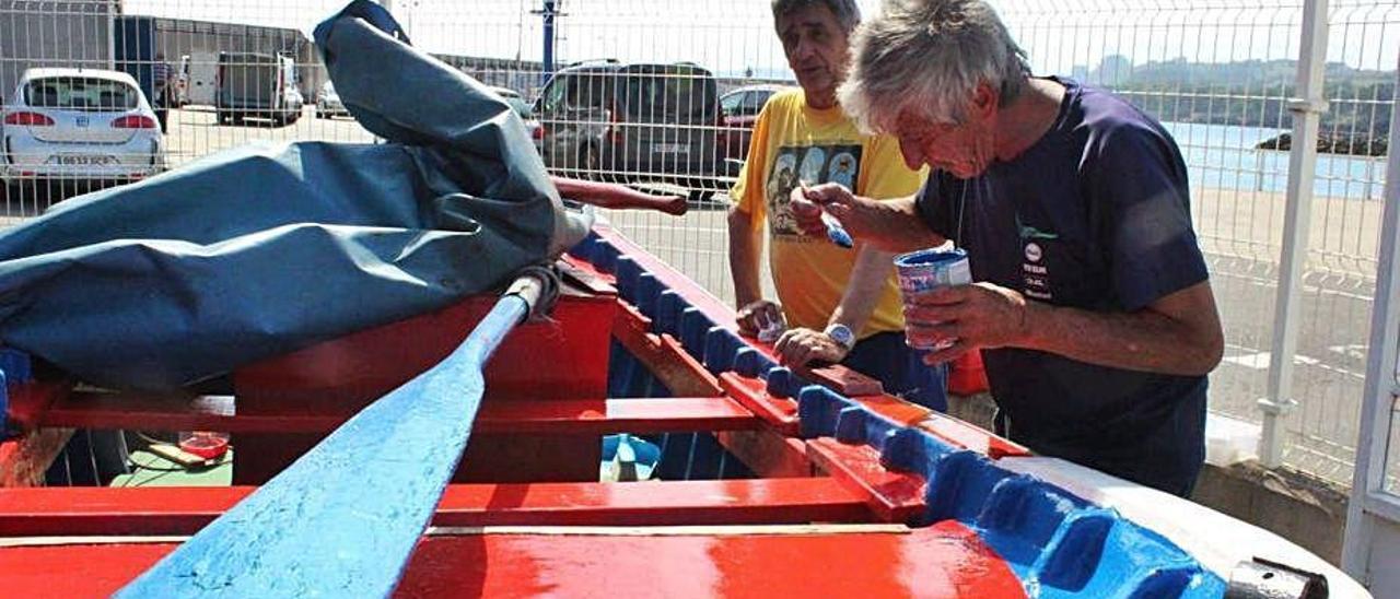 Enrique Fernández, &quot;Kaki&quot;, y Leopoldo García, &quot;Polo&quot;, pintando una lancha en el muelle de Candás.