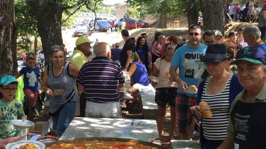 Los participantes en la fiesta degustan un plato de paella.