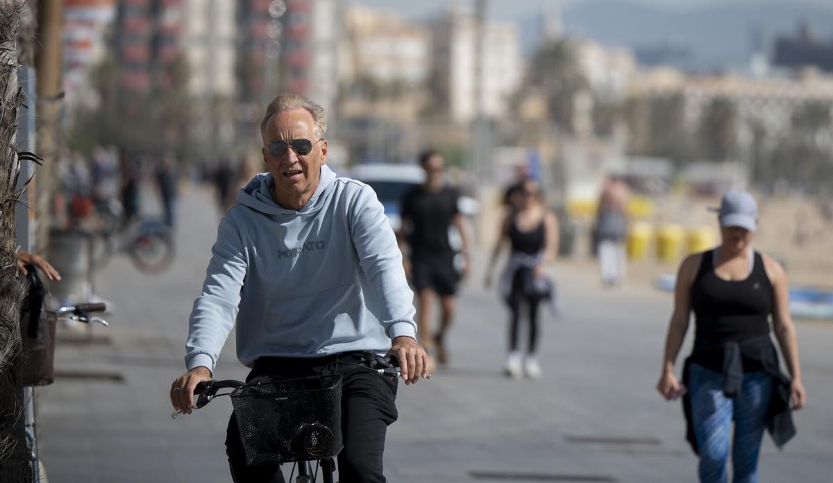 Un hombre monta en bicicleta junto a la playa de la Barceloneta.