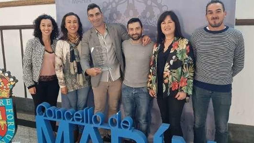 El joven posa con el galardón junto a representantes municipales.