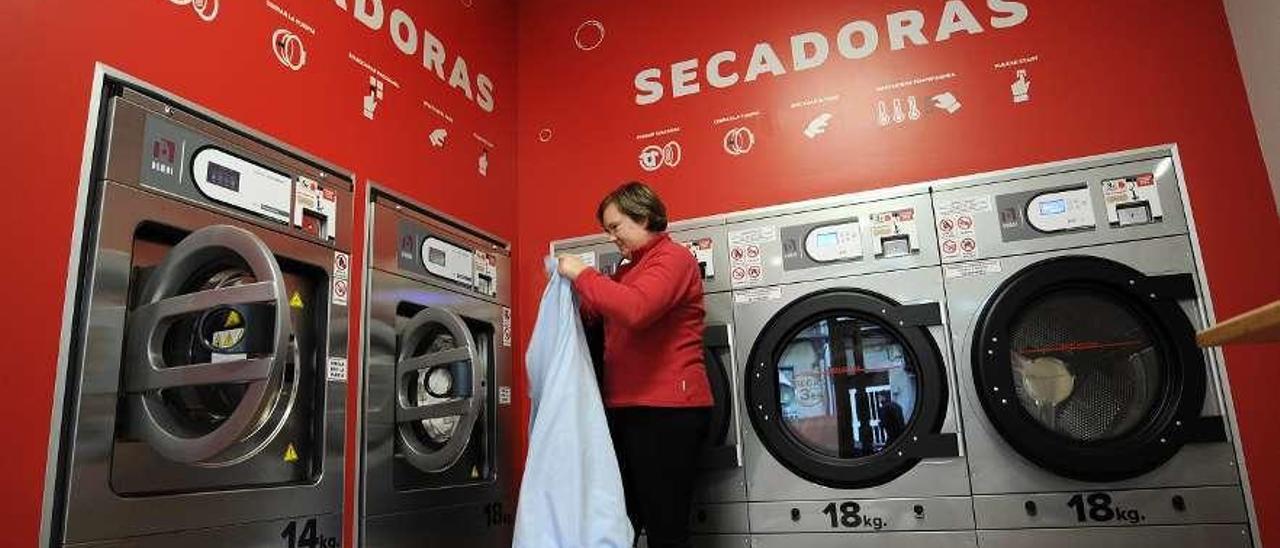 Un cliente introduce su ropa en una lavadora del autoservicio abierto en Silleda. // Bernabé/Javier Lalín