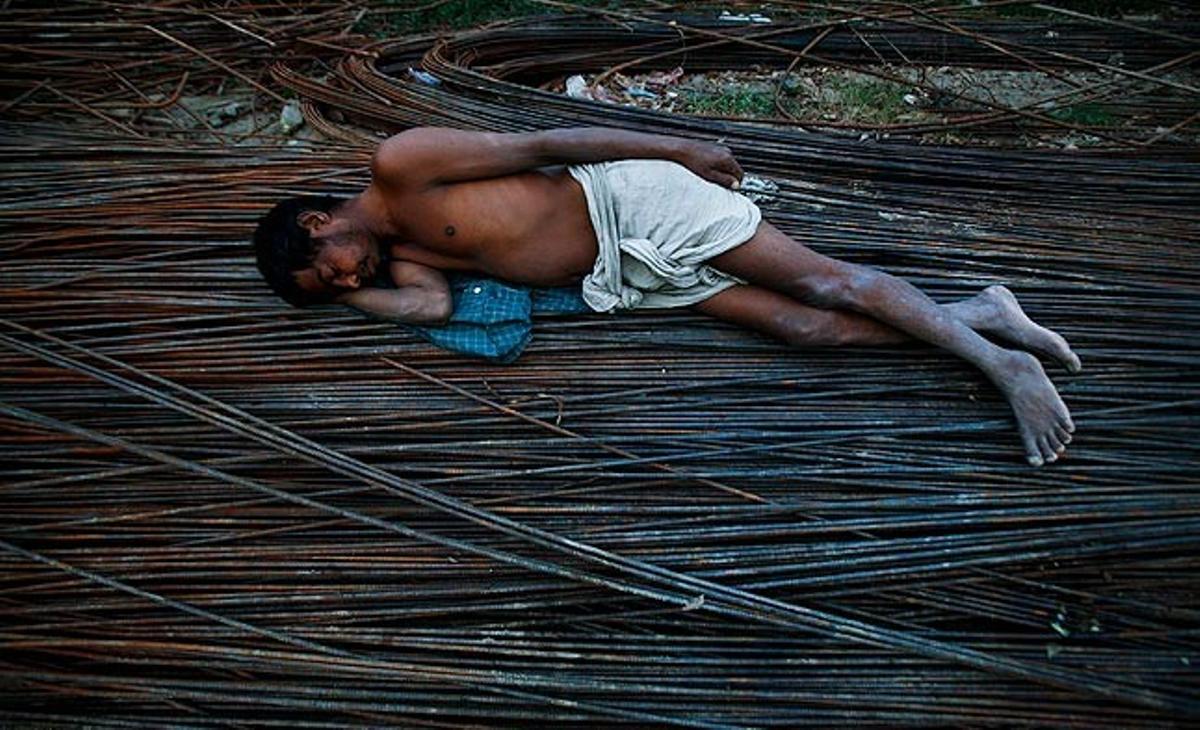 Un treballador pakistanès descansa aquest dilluns sobre unes barres d’acer de l’obra on treballa, a la població de Noida (estat d’Uttar Pradesh).