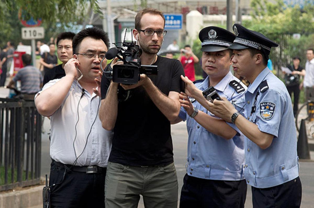 Agents de policia intenten impedir que els periodistes gravin davant el jutjat que ha prohibit a l’artista Ai Weiwei assistir a la primera sessió del judici per una demanda presentada per la seva empresa en contra de les autoritats fiscals, a Pequín.