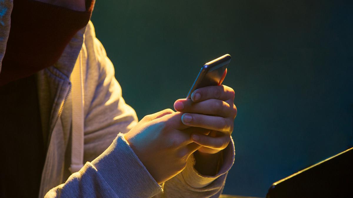 Un chico mira su teléfono móvil.