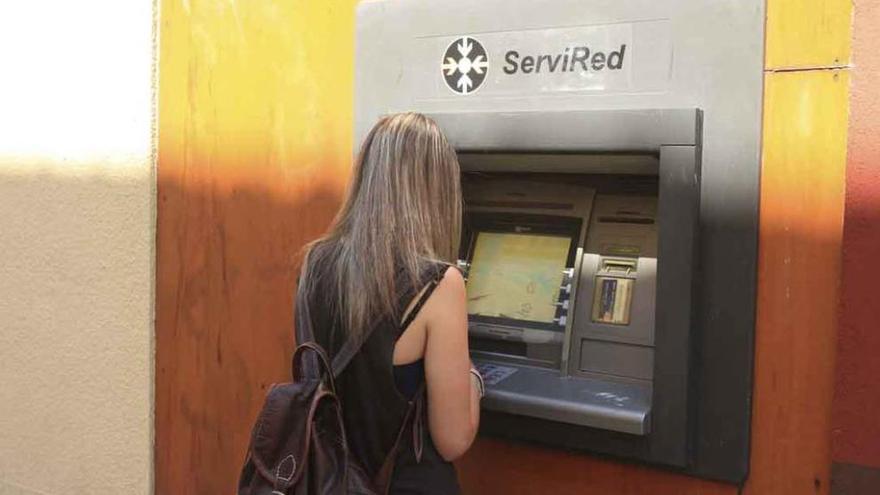 Una joven saca dinero de un cajero automático.
