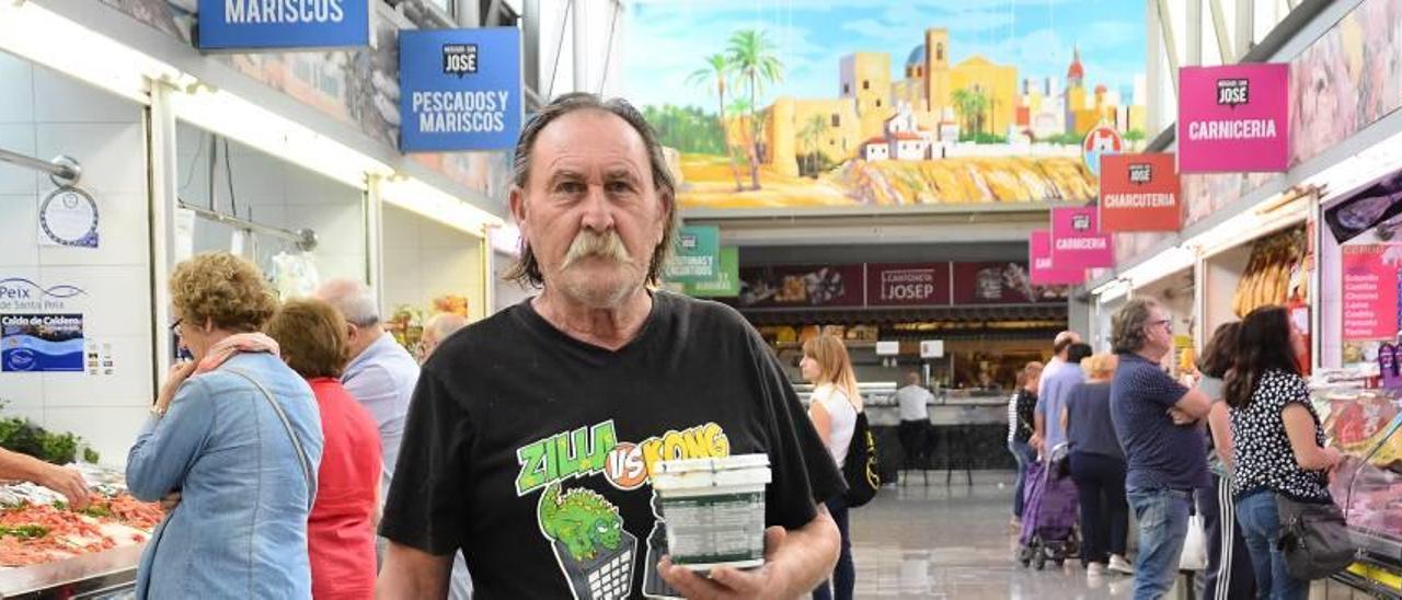 El pintor Manuel Blasco, con un bote de pintura en la mano, durante la mañana de ayer entre los puestos del mercado de San José, con uno de sus murales al fondo.