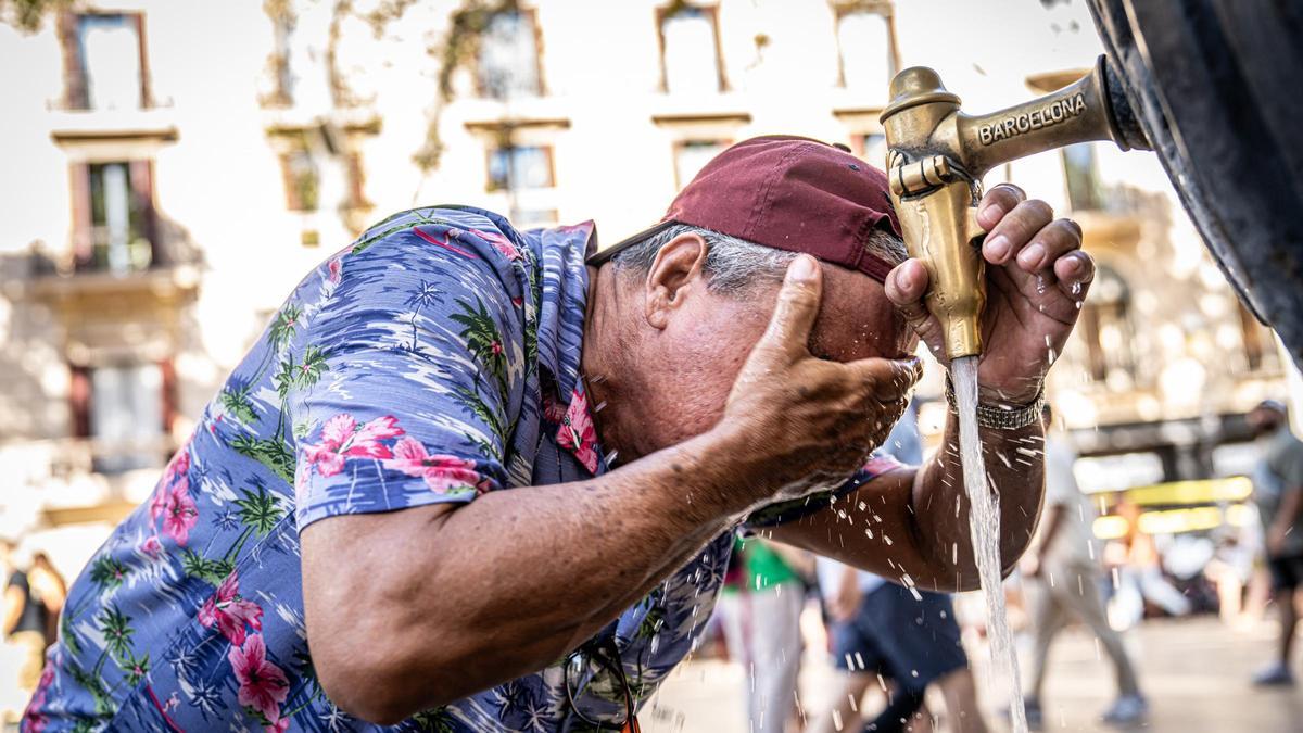 Un hombre se refresca en una fuente de Barcelona, este verano