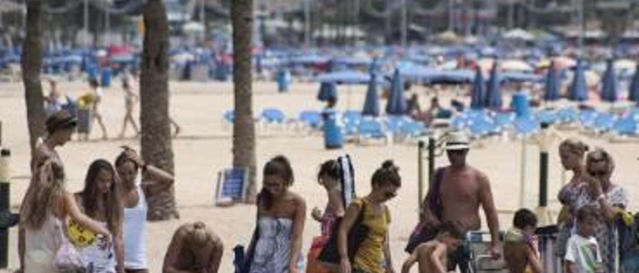 Bañistas utilizando una batería de lavapiés en la playa de Levante de Benidorm.