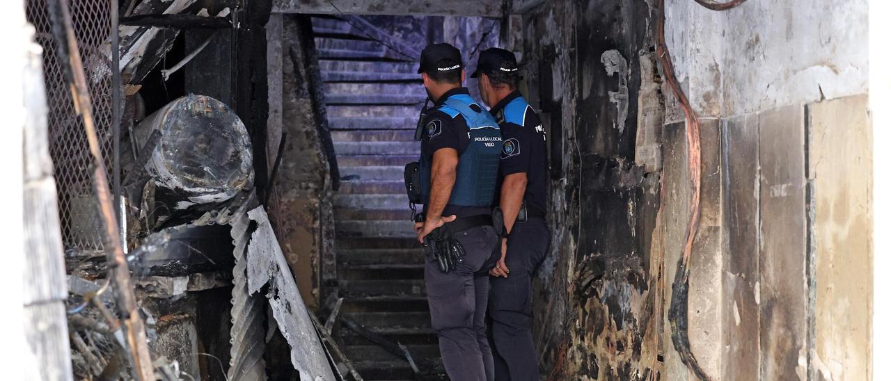 Dos policías inspeccionan el portal del edificio incendiado.