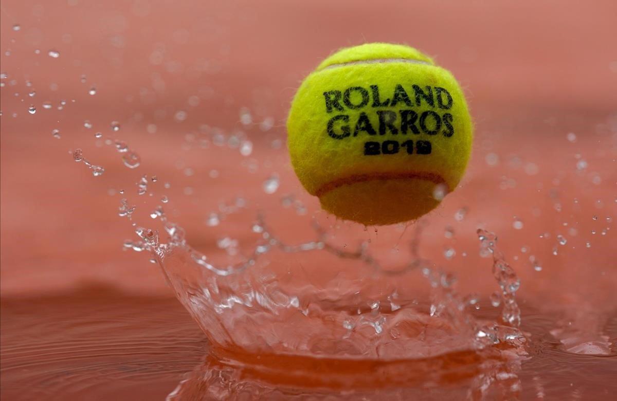 La pelota oficial del torneo Roland Garros rebota sobre la tierra empapada en París.