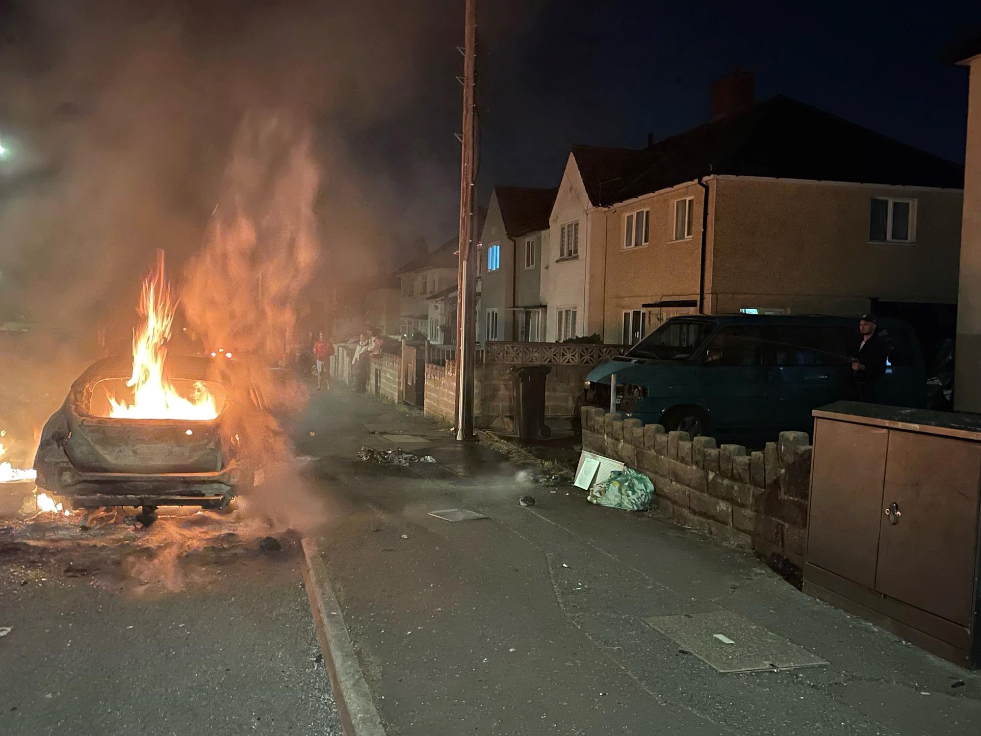 Un coche en llamas en el distrito de Ely, en Cardiff, el 22 de mayo de 2023, por unos disturbios tras la muerte de dos adolescentes en un accidente de tráfico.