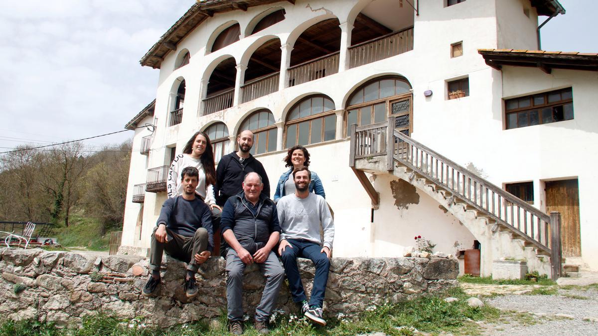 Els usuaris, el masover i els impulsors de Fem Coliving a Sant Joan de les Abadesses (Ripollès) amb el mas de fons