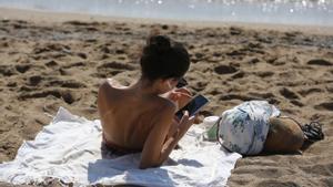 BARCELONA 05/08/2022 ECONOMIA Desconexión del trabajo pero con el mobil, gente en la playa de la barceloneta con el mobil en la mano FOTO ELISENDA PONS