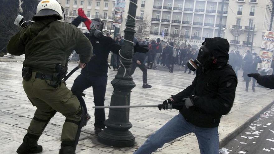Manifestantes radicales se enfrentan a un policía antidisturbios tras la manifestación de Atenas.
