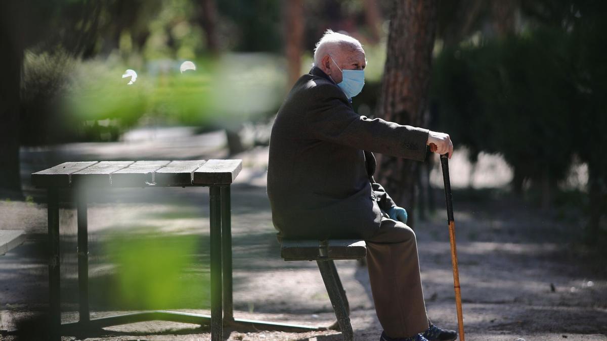Un anciano con mascarilla descansa en el Parque Calero, en el distrito de Ciudad Lineal de la capital.