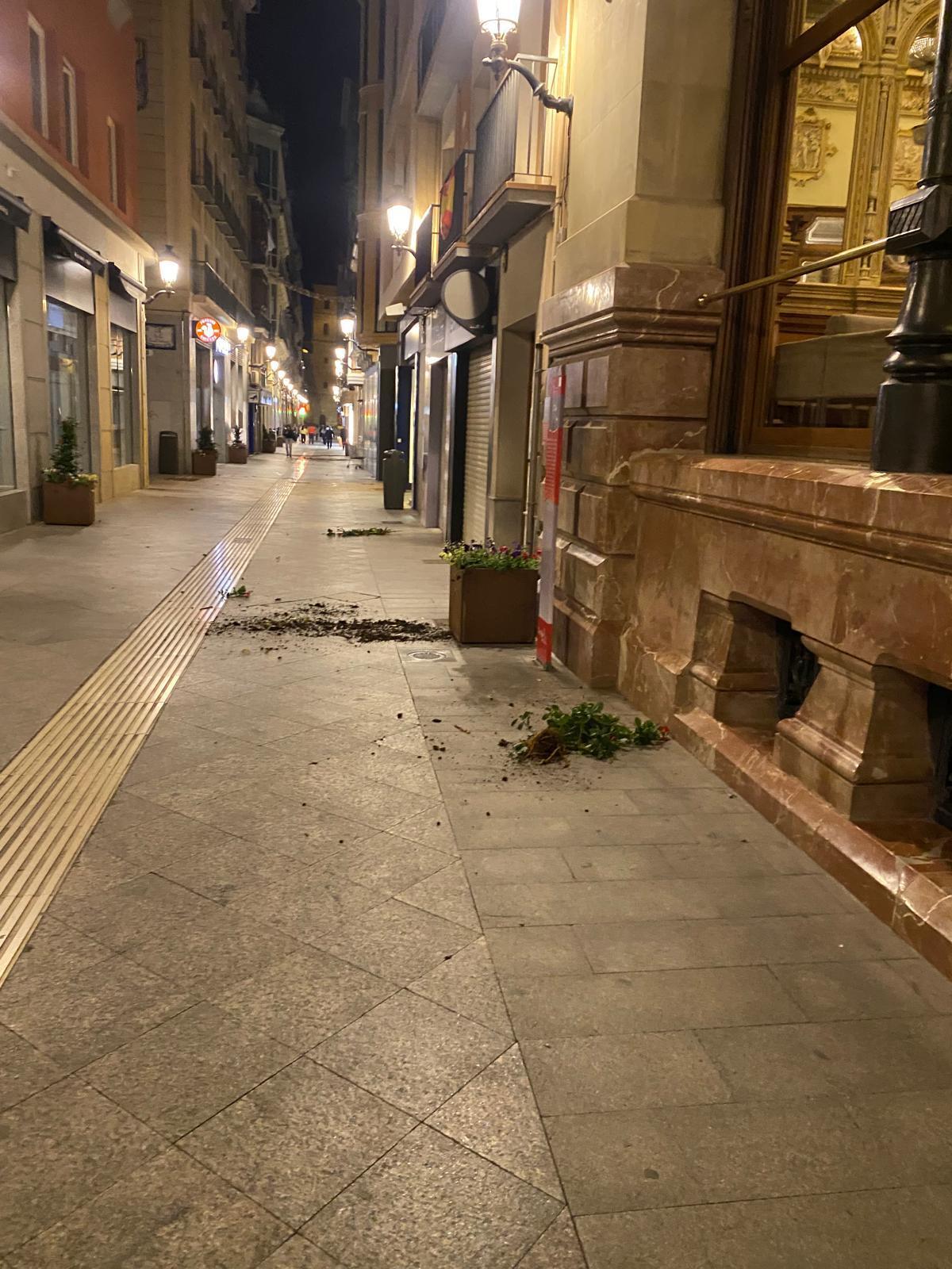 Así lucía anoche la calle Trapería, en la entrada del Real Casino de Murcia, con restos del macetero arrancado para lanzar a las puertas.