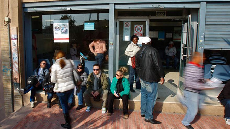 Varias personas esperan junto a una oficina de empleo.