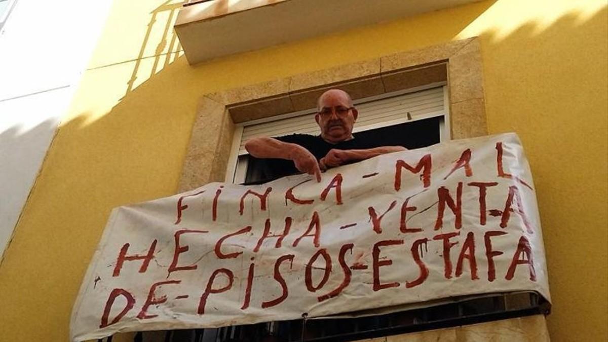 Manuel Mir Cruañes en el balcón de su casa, del que ha colgado una pancarta
