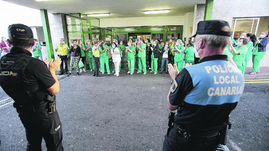 Dos funcionarios policiales aplauden al personal sanitario de La Candelaria.