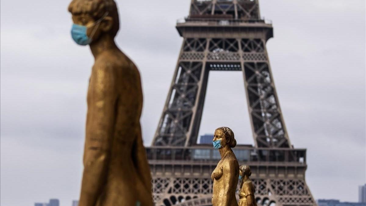 Las estatuas doradas de la explanada de Trocadero, frente a la Torre Eiffel, están cubiertas con máscaras protectoras en París.