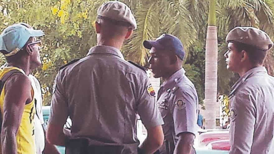 Hay mucha vigilancia policial, sobre todo al oscurecer, por el centro de La Habana. Abajo, el autor del reportaje, entrevistado en la calle.