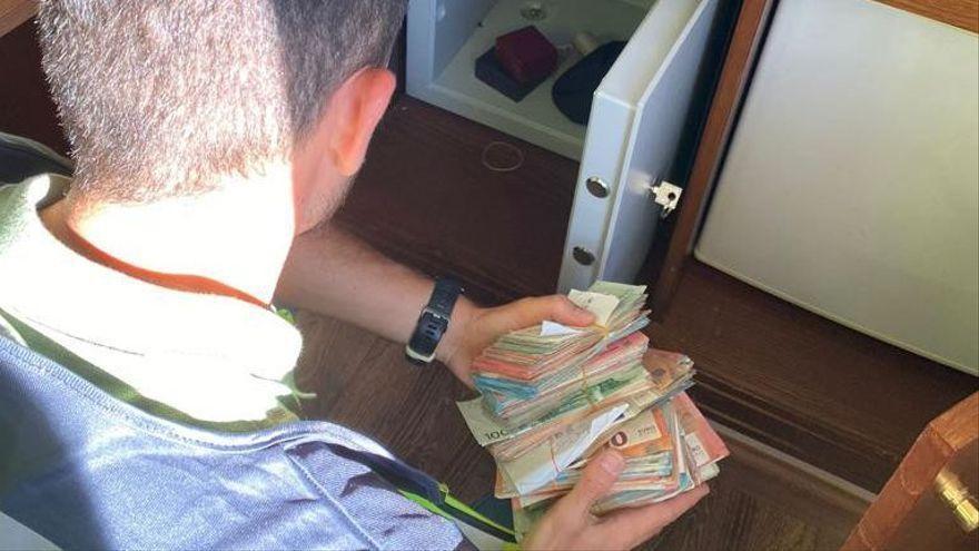 Un agente de Policía, con parte del dinero intervenido en casa de uno de los detenidos. CNP