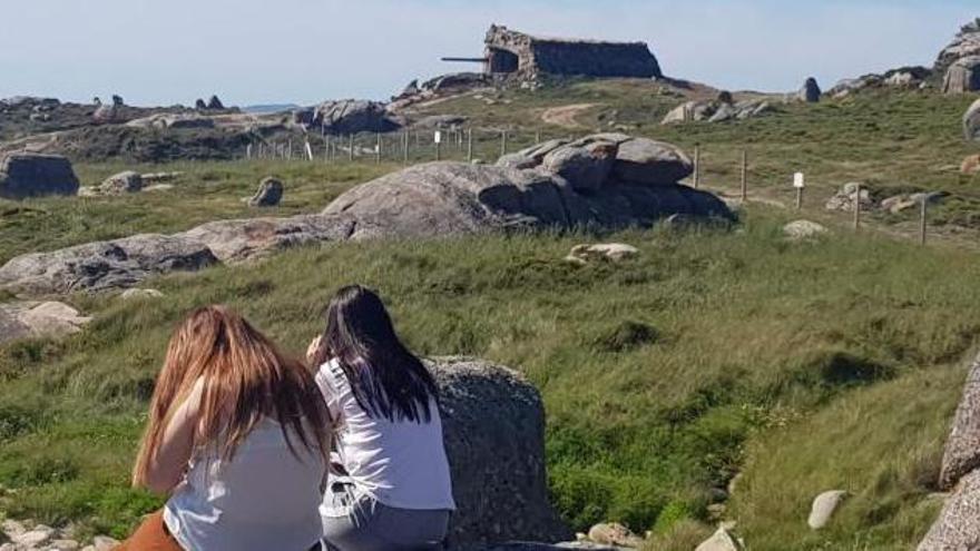 Dos jóvenes en Con Negro, con uno de los cañones de la batería militar al fondo.