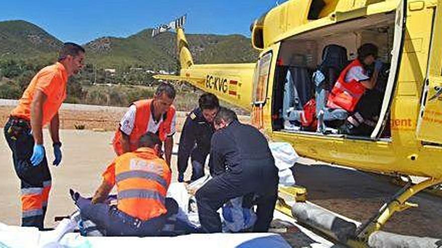 Tripulantes del helicóptero y personal del 061 suben a un paciente para su traslado.