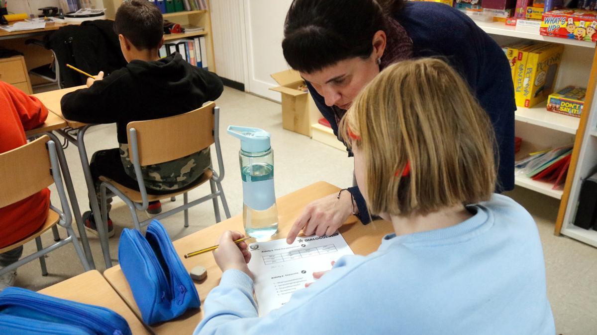 Una mestra d'una escola gironina ajudant una alumna en una aula on han arribat infants procedents d'Ucraïna.