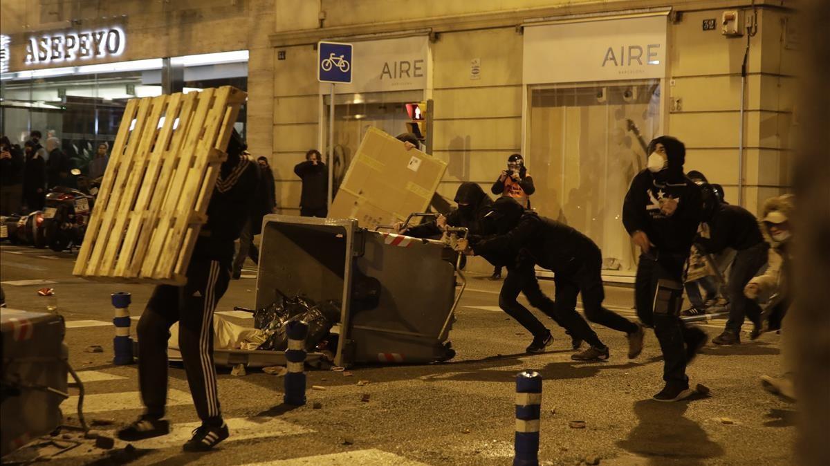 Manifestantes vuelcan contenedores para quemarlos durante la manifestación por la detención de Hasél, este martes en Barcelona.