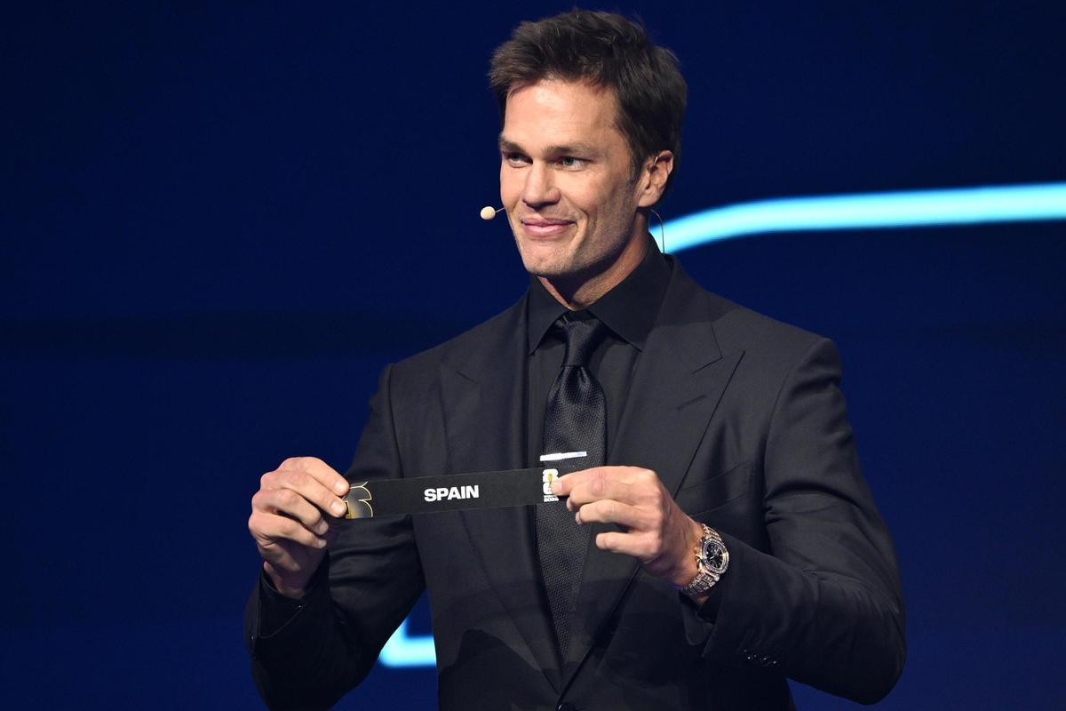 La estrella de fútbol americano, Tom Brady,  sujeta la papeleta con el nombre de Spain durante el sorteo del Mundial 2026