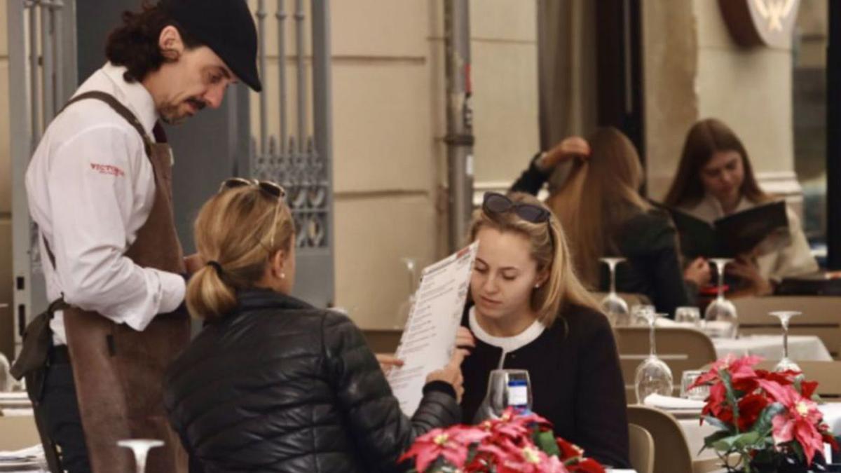 Un camarero atiende a dos clientes en un restaurante de Málaga.