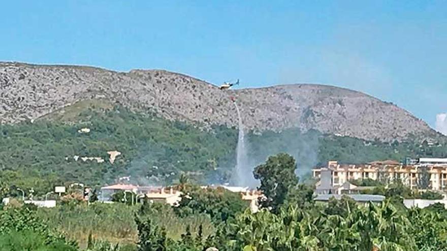 Un helicóptero del Ibanat arroja agua, ayer, en el Port d´Alcúdia en el solar situado junto a la gasolinera.