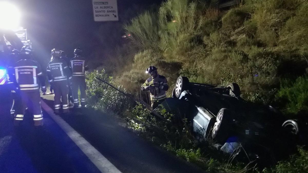 Bomberos de Murcia trabajan en el lugar del suceso, con el coche ruedas arriba.