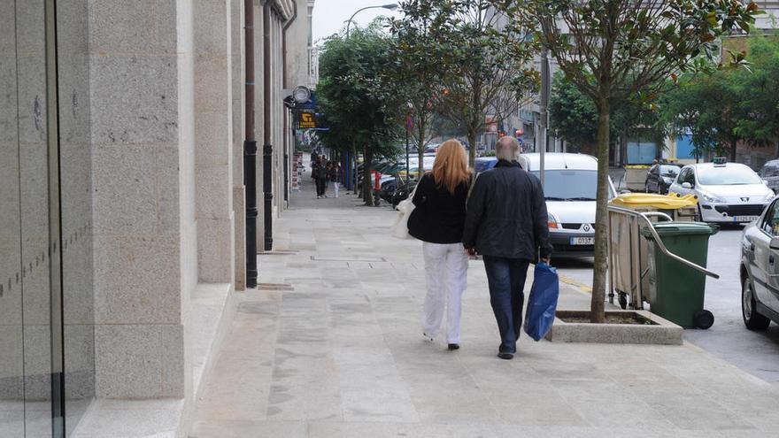 Dos personas pasean por la calle Hospital, con decenas de árboles en las aceras.