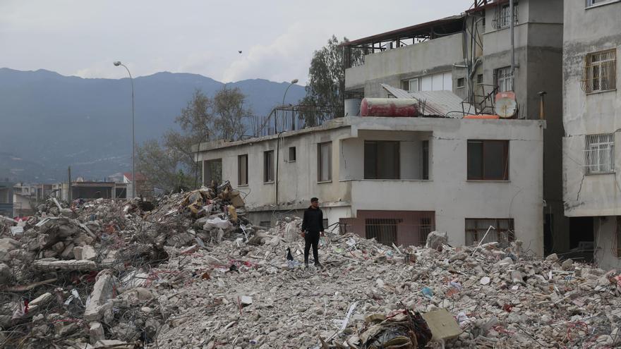 Un joven observa la destrucción causada por los seísmos en la región turca de Hatay, encaramado a una montaña de escombros.