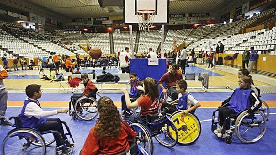 Els participants a la jornada jugant a bàsquet en cadira de rodes, al pavelló de Fontajau.