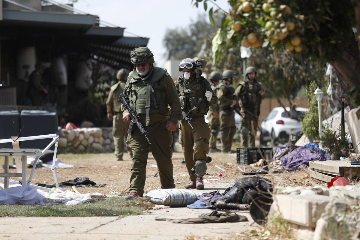 Soldados israelíes caminan junto a cadáveres de milicianos de Hamás en el kibbutz Kfar Aza, este martes.
