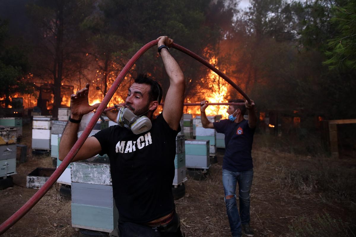 Bomberos y voluntarios trabajan en la extinción del fuego en Varybobi, al noreste de Atenas.