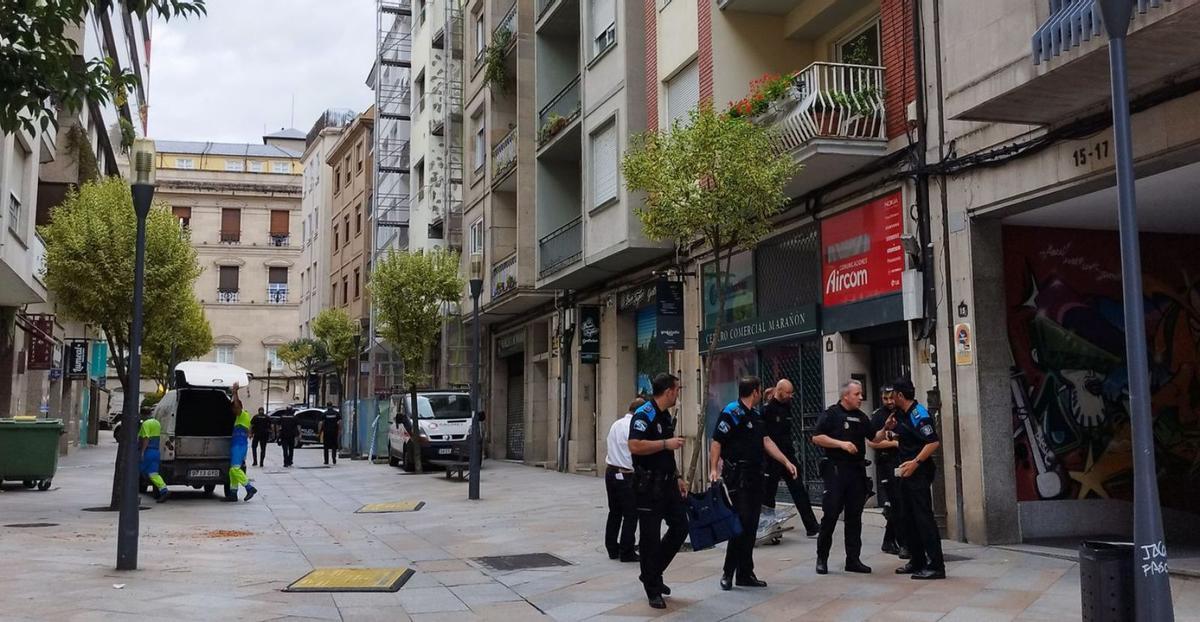 Policías a las puertas del lugar del incidente, mientras operarios limpian la calzada. |   // FERNANDO CASANOVA