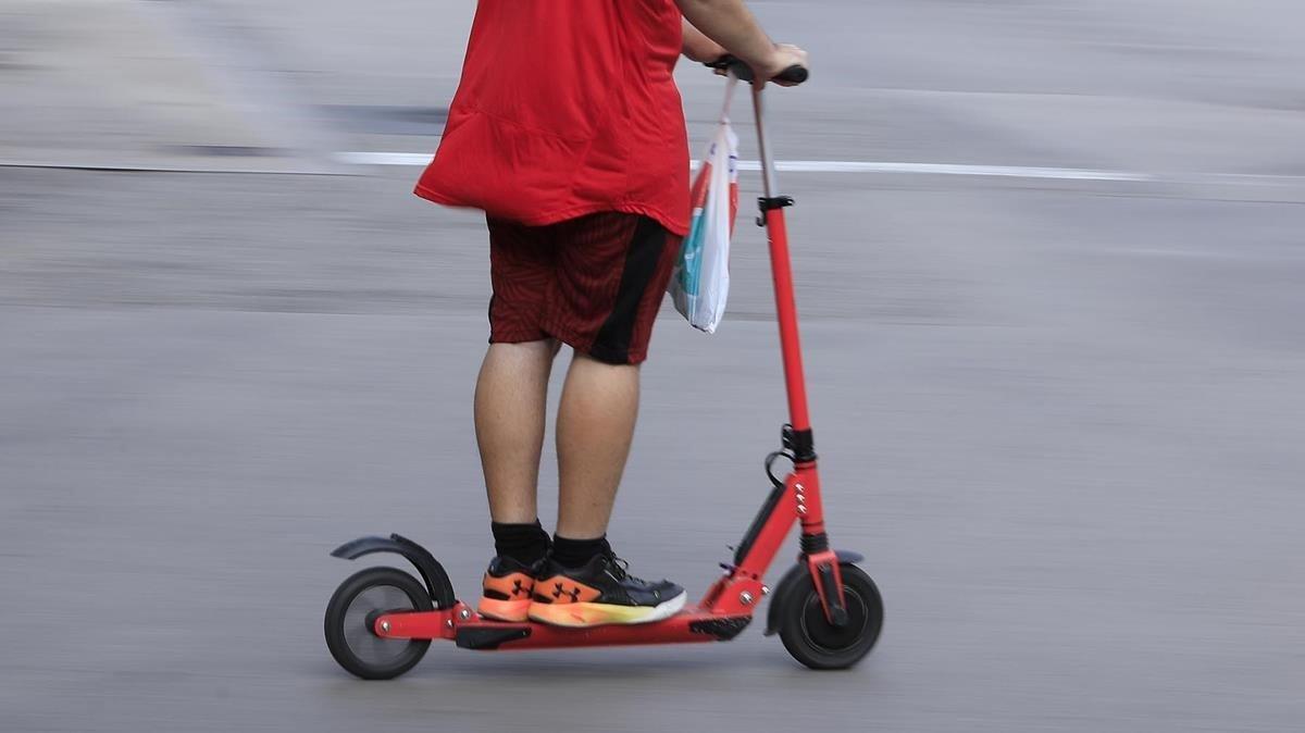 Un menor con un patinete en una calle de Barcelona.