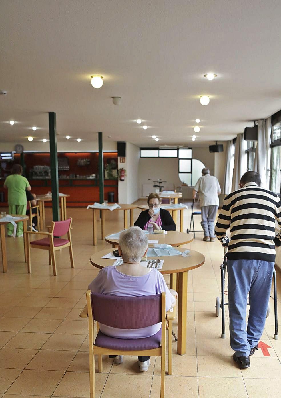 Usuarios del centro de día de Jardín de Cantos, en Avilés, se dirigen al comedor en la hora de la comida.  