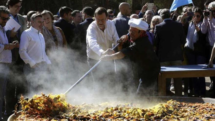 Mariano Rajoy ayuda a preparar una monumental paella, ayer en el día del afiliado en Zaragoza. // Efe