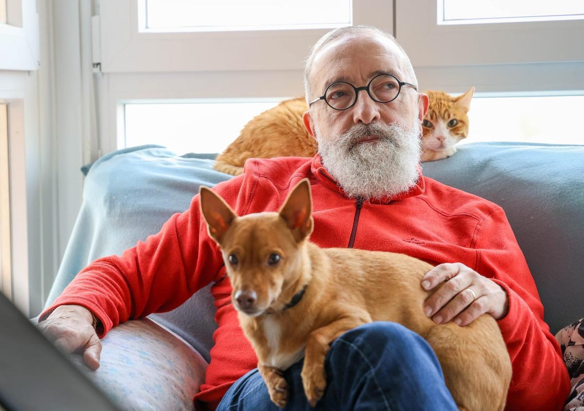 Amadeo escucha el concierto en su casa mientras sostiene a su perro Teddy y Garfield se tumba en el respaldo del sofá