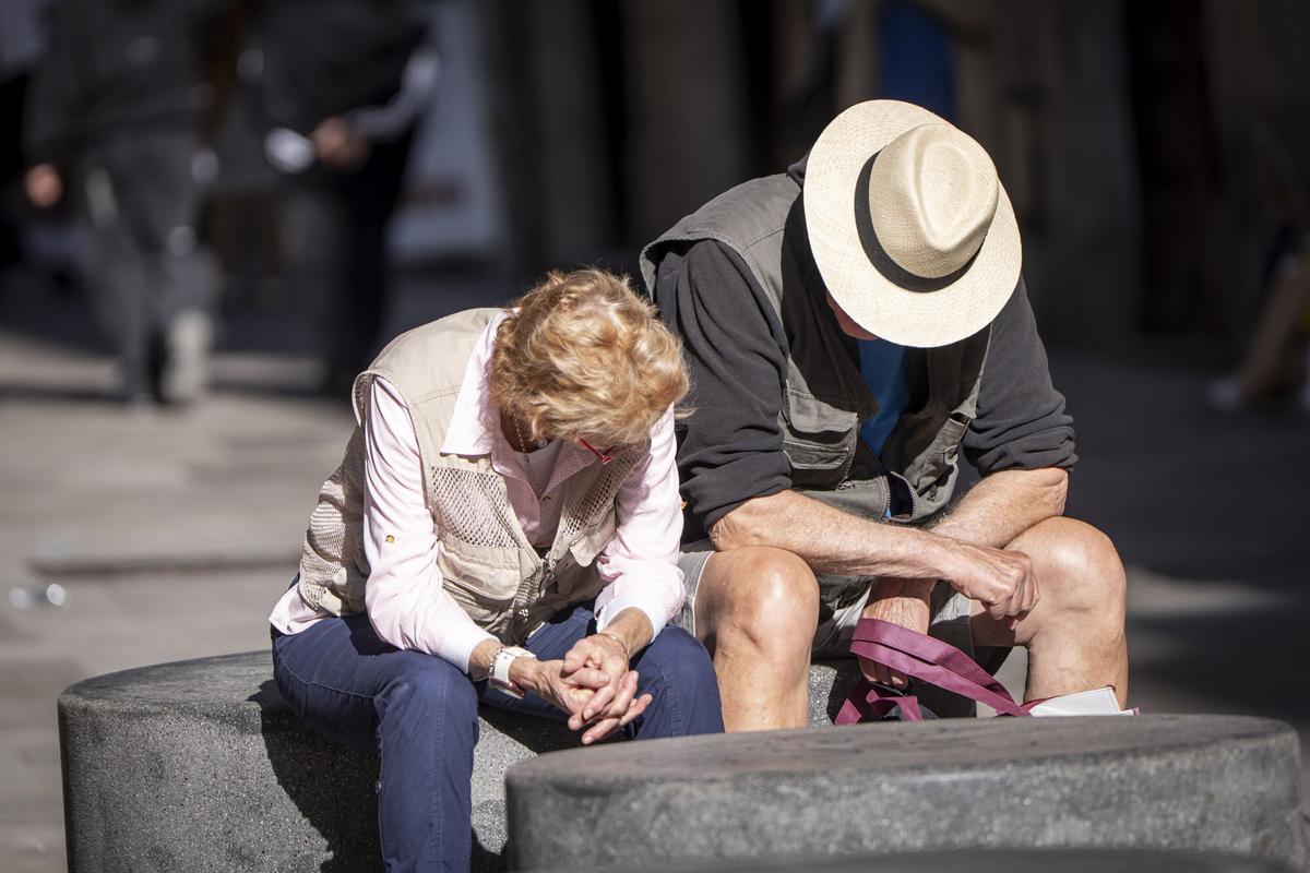Una pareja de jubilados sentados en un banco.