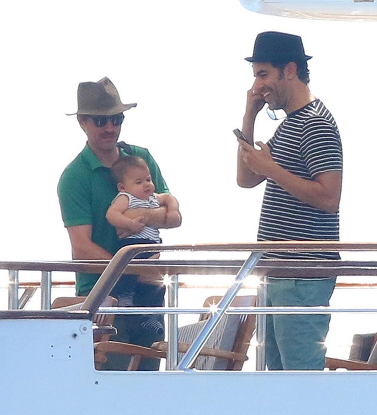 Sacha Baron Cohen habla por teléfono mientras un amigo tiene a su hijo pequeño en brazos