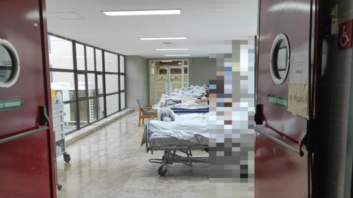 Pacientes en un corredor sin cortinas en el Hospital de la Ribera.